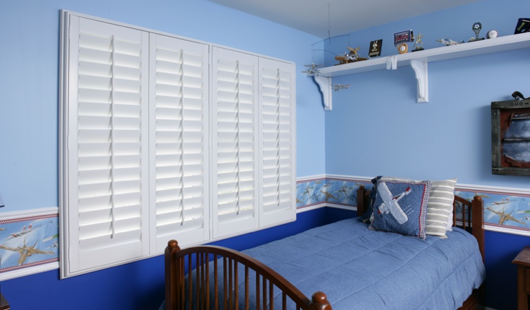 Large plantation shutters covering window in blue kids bedroom in Las Vegas 